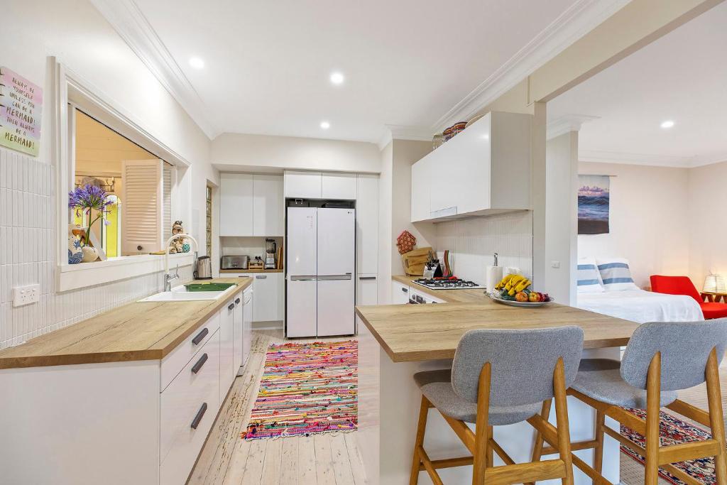 a kitchen with white cabinets and a kitchen island with chairs at Family stay minute walk from Hargraves beach in Norah