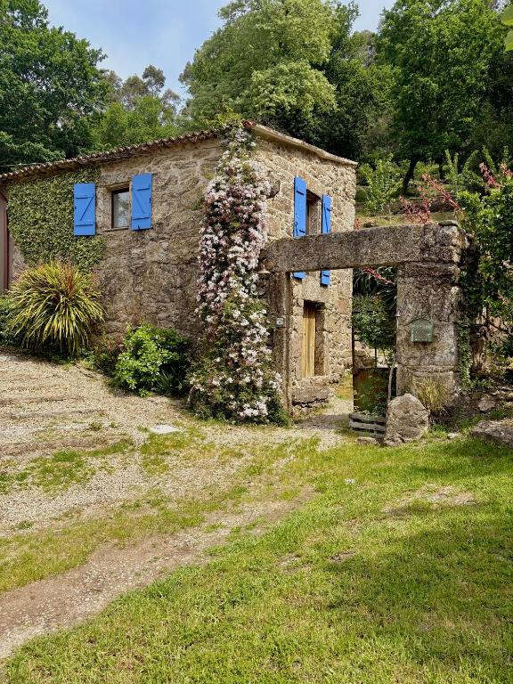 an old stone house with blue windows and flowers at Entrerobles - Casiña Cereixa in La Cañiza