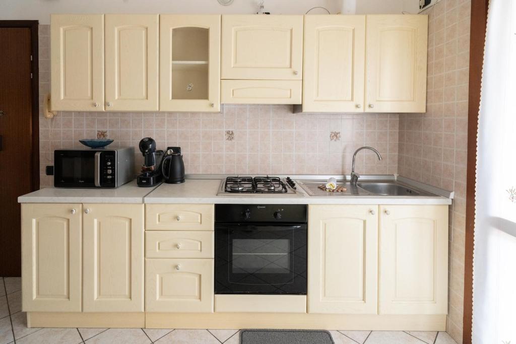 a kitchen with white cabinets and a stove and a sink at A Due Passi dal Mare in Chioggia