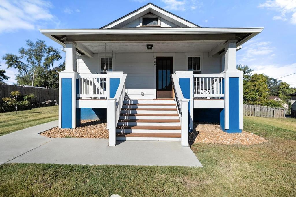 a small white house with blue columns and stairs at The Barker Bungalow in St. Charles