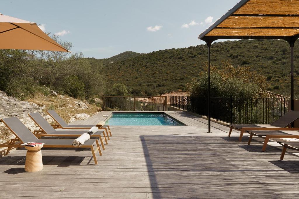 a swimming pool with lounge chairs and an umbrella at Villa Nebbiu Vista in Oletta