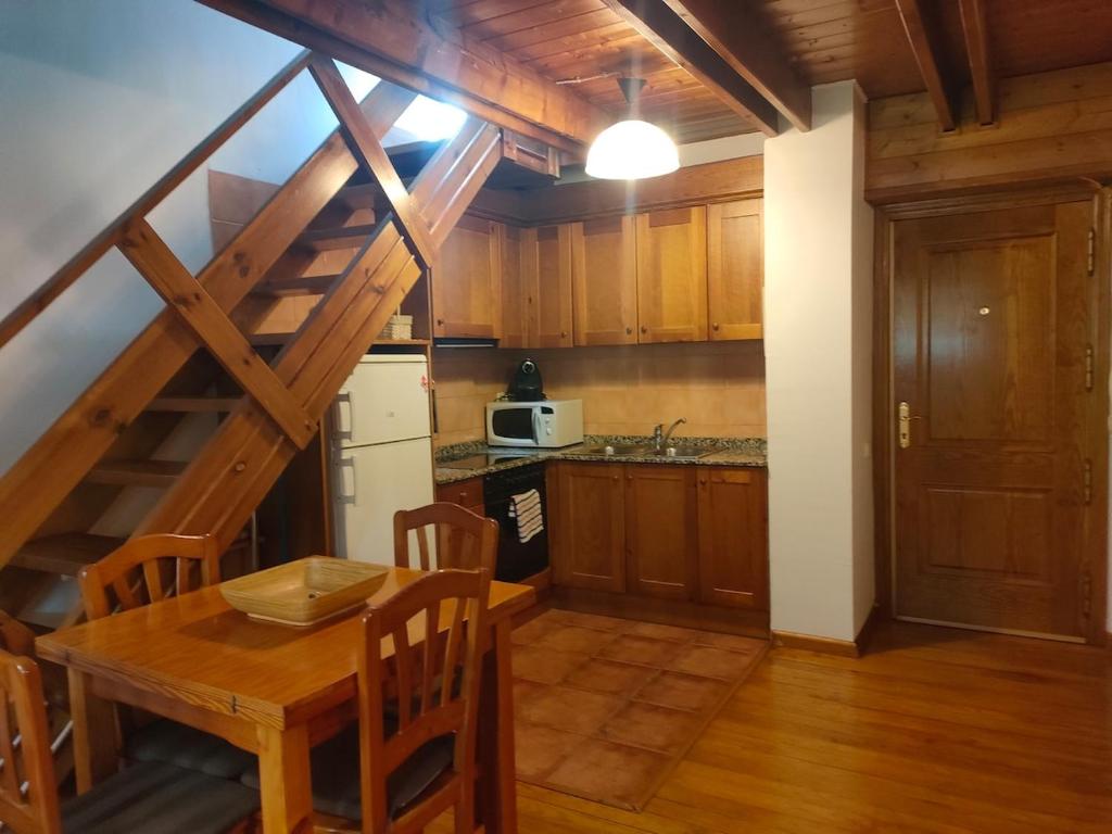 a kitchen with a wooden table and a wooden staircase at Barruera duplex 2 bedrooms heating in Barruera