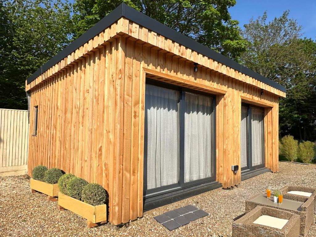 a wooden shed with a black roof and two windows at Longovers Lodge in Westbourne