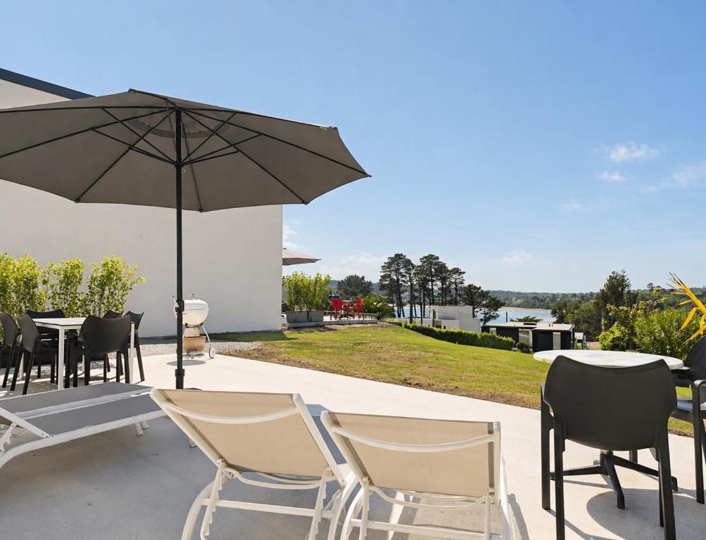 a patio with tables and chairs and an umbrella at La Maison des Falaises in Crozon