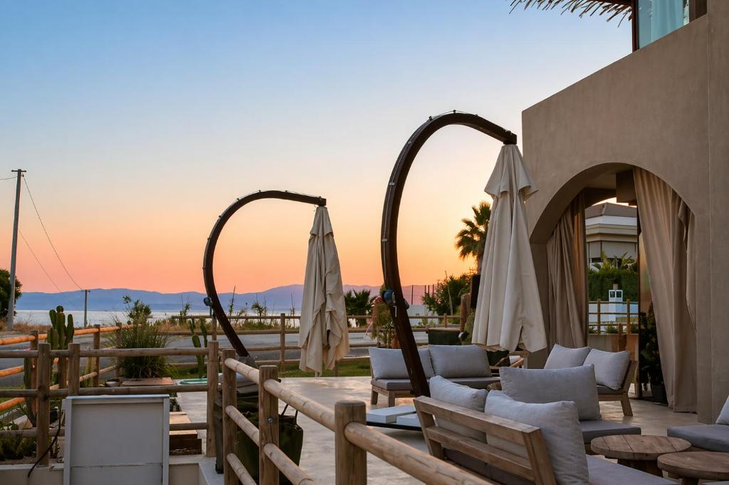 a patio with chairs and umbrellas at sunset at No908 Sunset HOTEL in Çeşme
