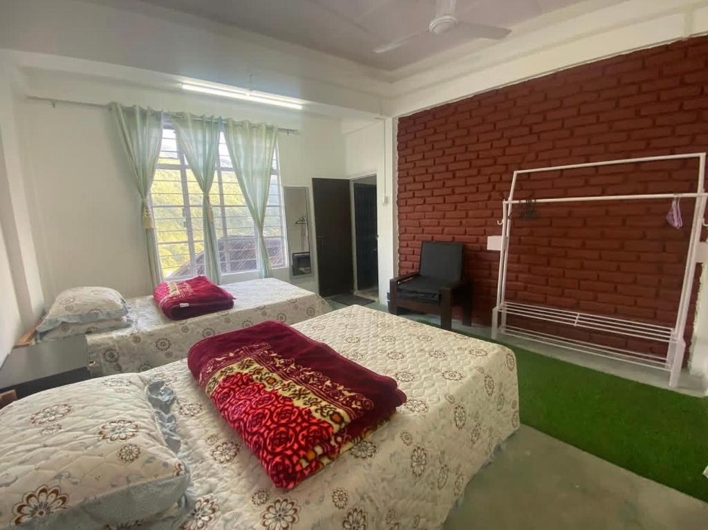 a bedroom with two beds and a brick wall at Saus Home in Khonoma