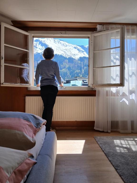 a woman looking out of a window at a mountain at Hostel Engelberg "mein Trail Hostel" in Engelberg