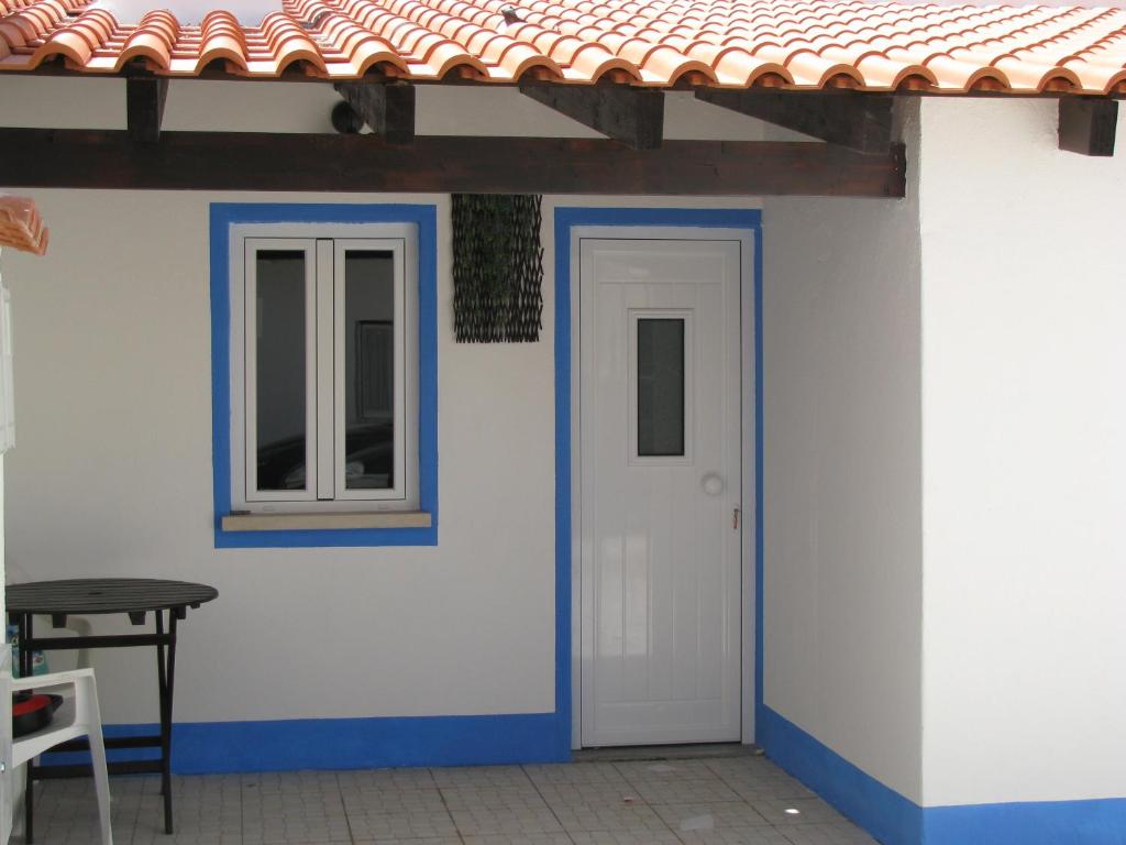 a white and blue house with a door and a window at Galega Guest House in Nazaré