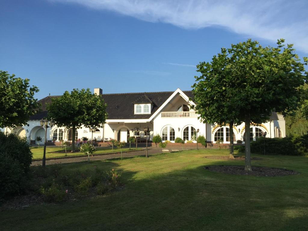 een groot wit huis met een boom in de tuin bij Apartment Maasheuvel in Arcen