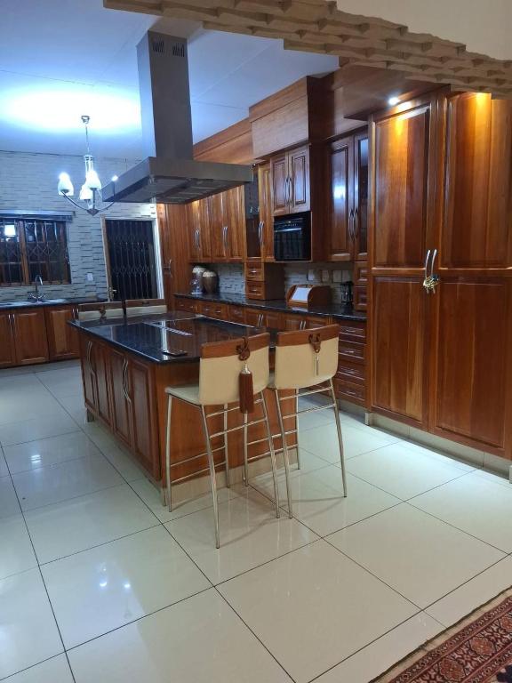 a kitchen with wooden cabinets and a island with stools at The Address Luxurious in Midrand