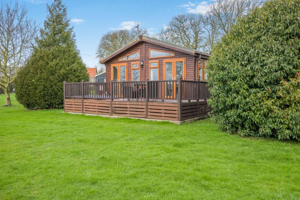 a large wooden cabin in a field of grass at Field View 1 bed-No Pets- Walnut in Eye