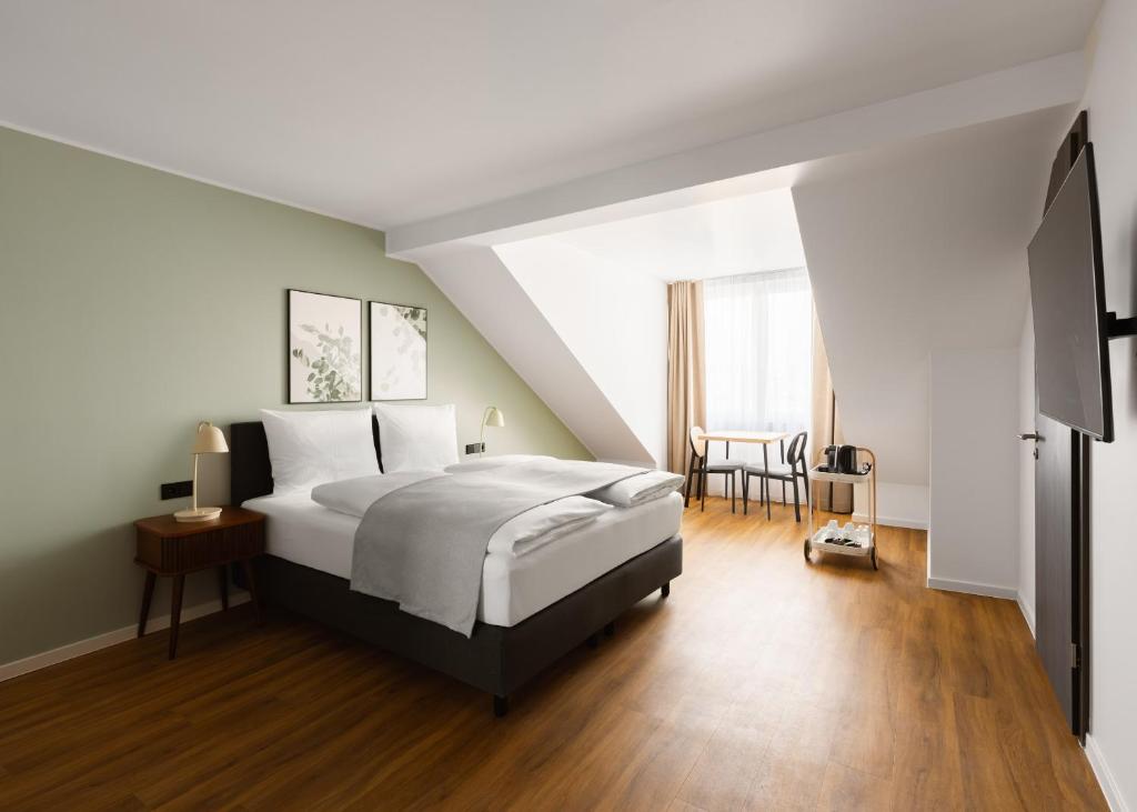 a bedroom with a large bed and a table at Limehome Düsseldorf Pionierstraße in Düsseldorf