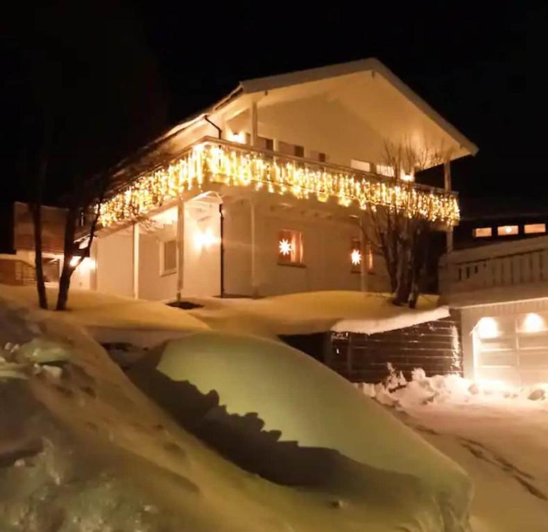 a house decorated with christmas lights in the snow at Smørblomstvegen Apartment in Tromsø