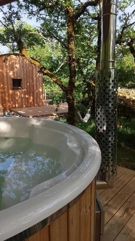 a jacuzzi tub in a backyard with a tree at La nuitée belle in Cénevières