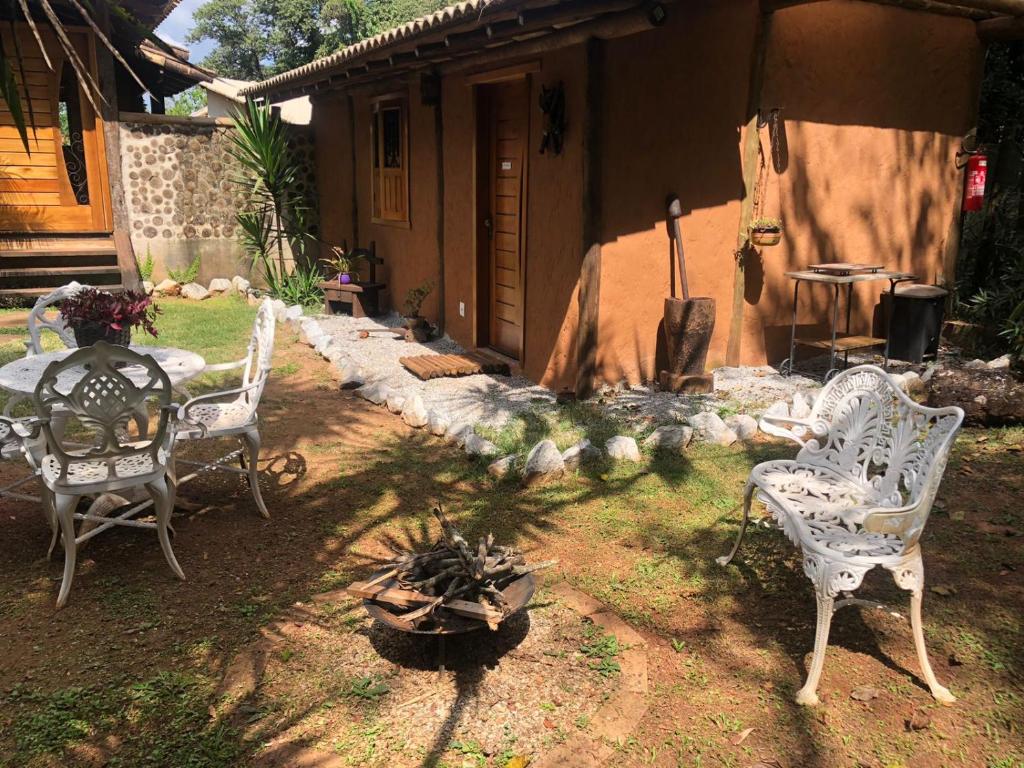 a patio with two white chairs and a table at Chalé Medieval in Brumadinho