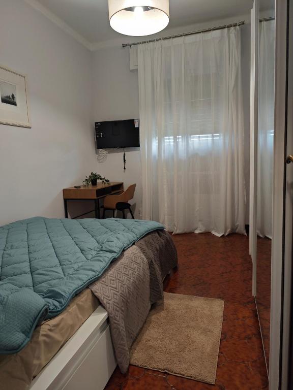 a bedroom with a bed and a desk and a television at Casa Largo Giusti in Vercelli