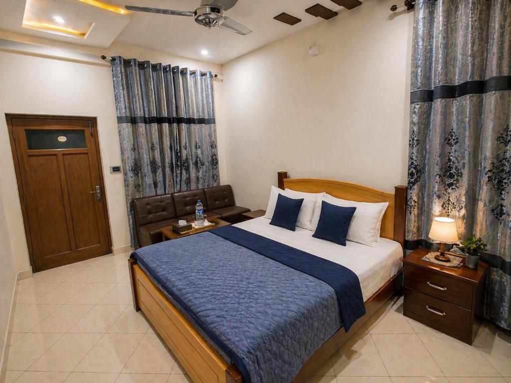 a bedroom with a large bed with a blue blanket at Second Home Hotel in Multan