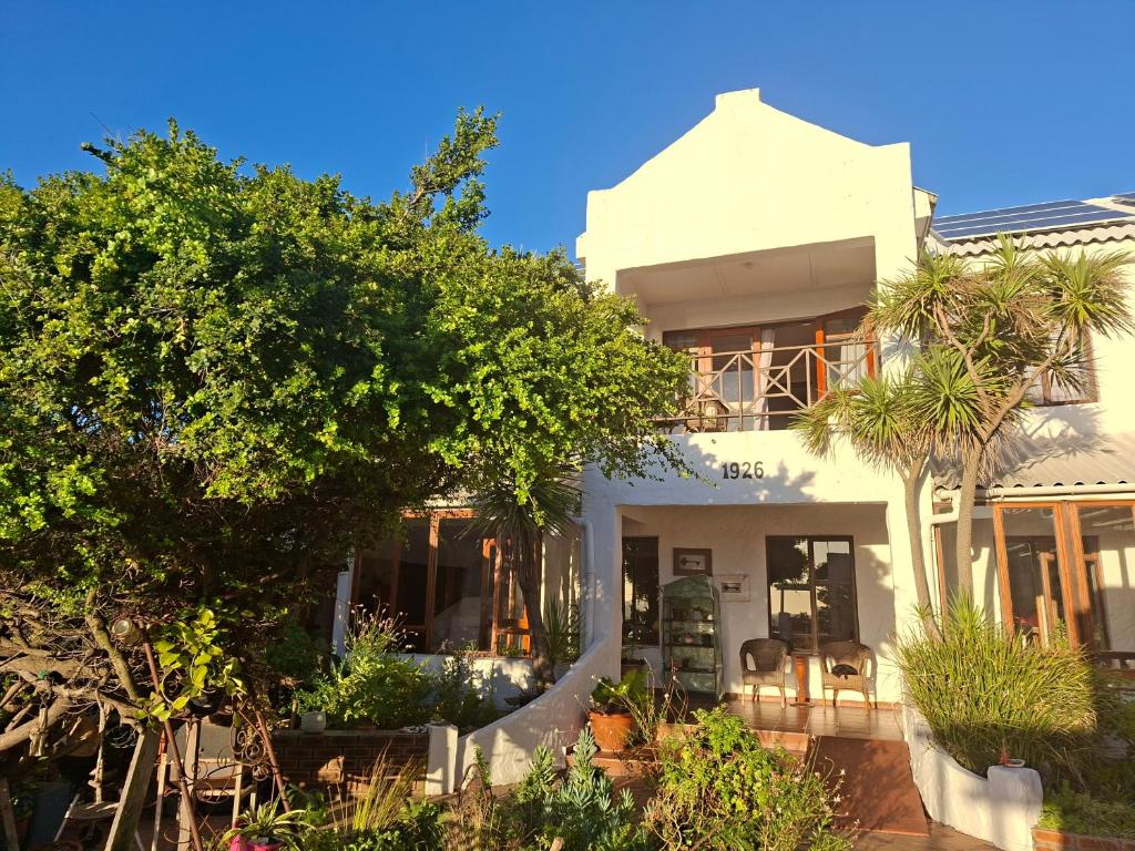 a white house with trees in front of it at Saxon Lodge in Gansbaai