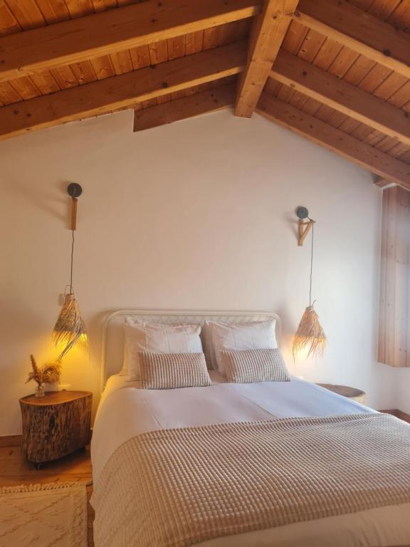 a bedroom with a large bed with wooden ceilings at Alba Odeceixe - casa clara in Odeceixe