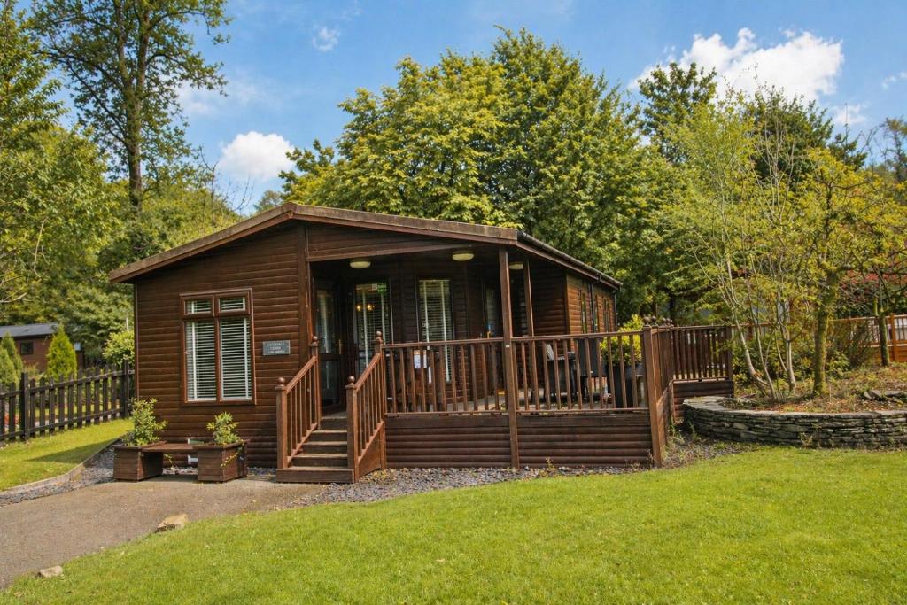 a small cabin with a porch and a fence at Grasmere 12, White Cross Bay, Windermere in Troutbeck Bridge