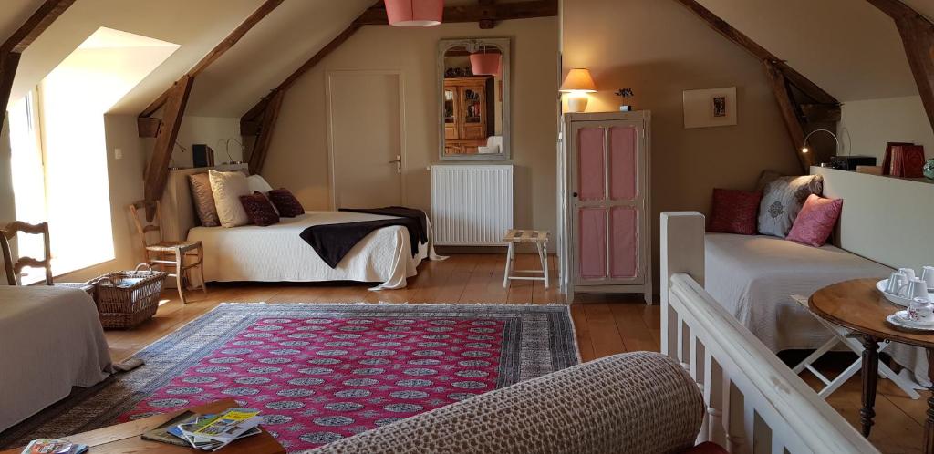 a attic room with two beds and a rug at La Peuterne in Mouazé