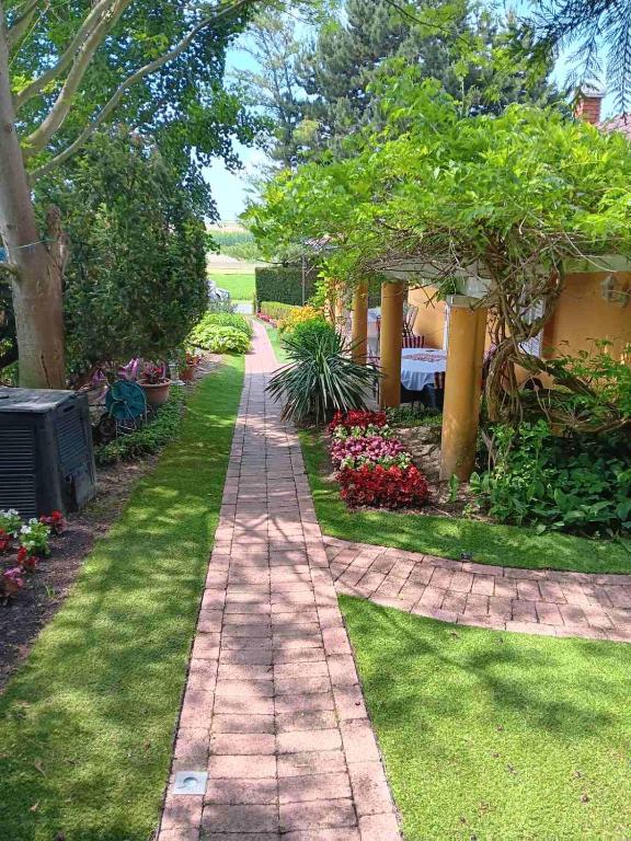 a brick path in a garden with flowers and trees at La Dolche Villa in Szőlősgyörök