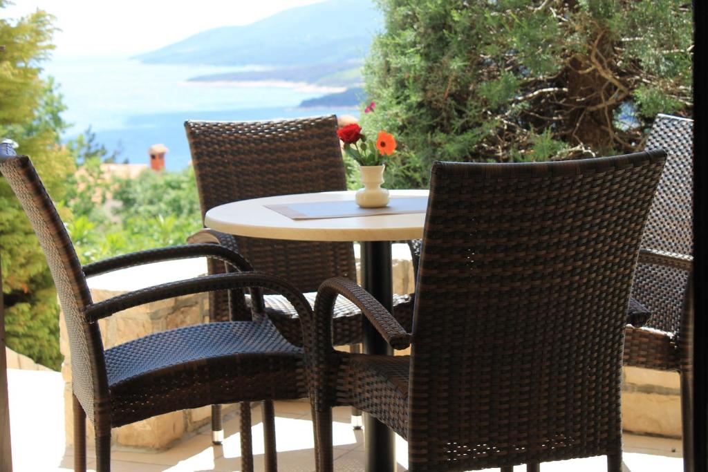 a table and chairs on a patio with a table and flowers at V Apartment in Rabac