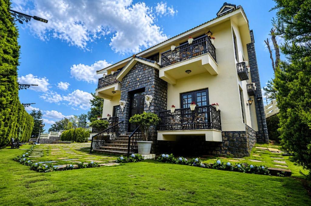 a house with a green yard at Lynton Resorts in Kotagiri