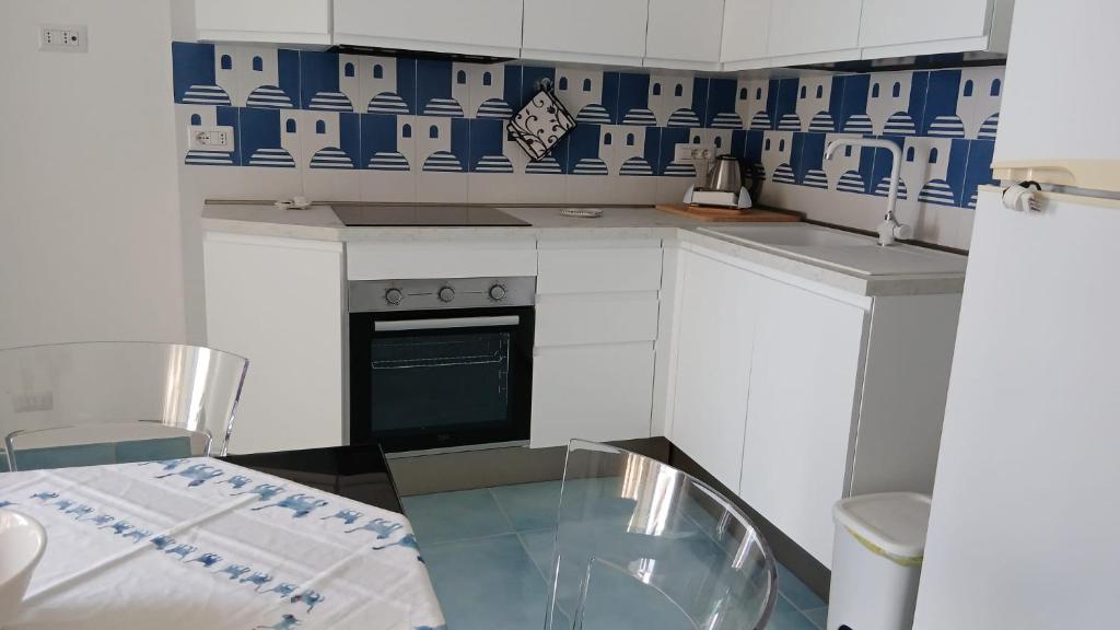 a small kitchen with a glass table and blue and white tiles at Venti In Costa in Furore