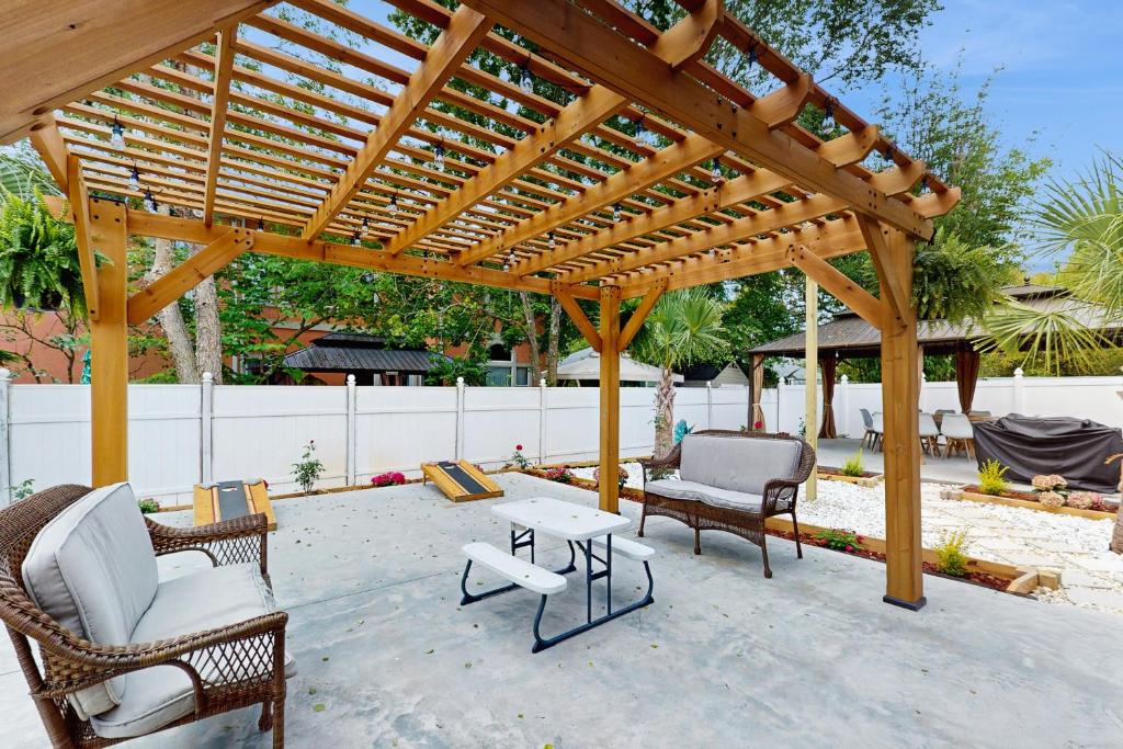 a wooden pergola with chairs and tables on a patio at 2 Mi to Beach! Group-Friendly Navarre Getaway in Navarre