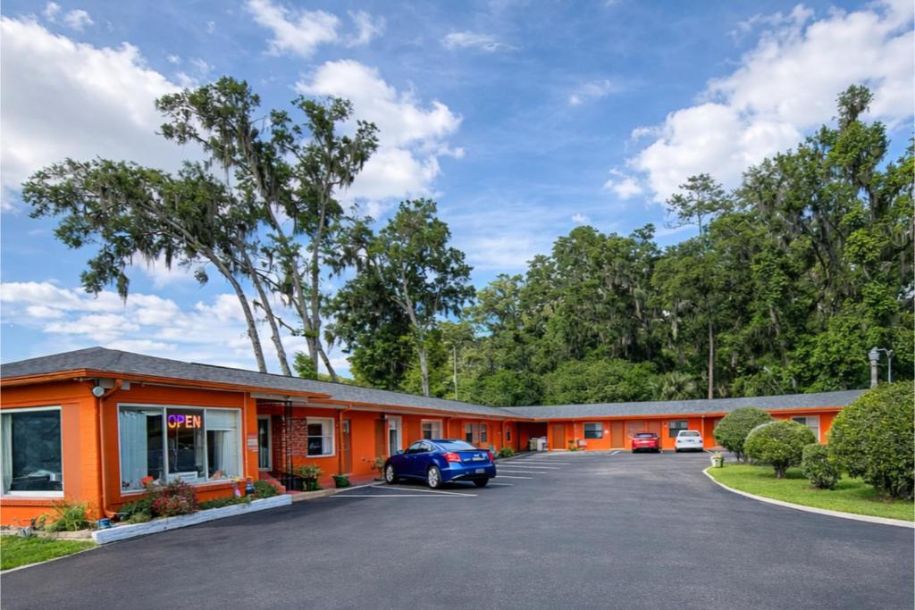 an orange motel with a car parked in the parking lot at Stevens Motel by Capital O Ocala US 27 in Ocala