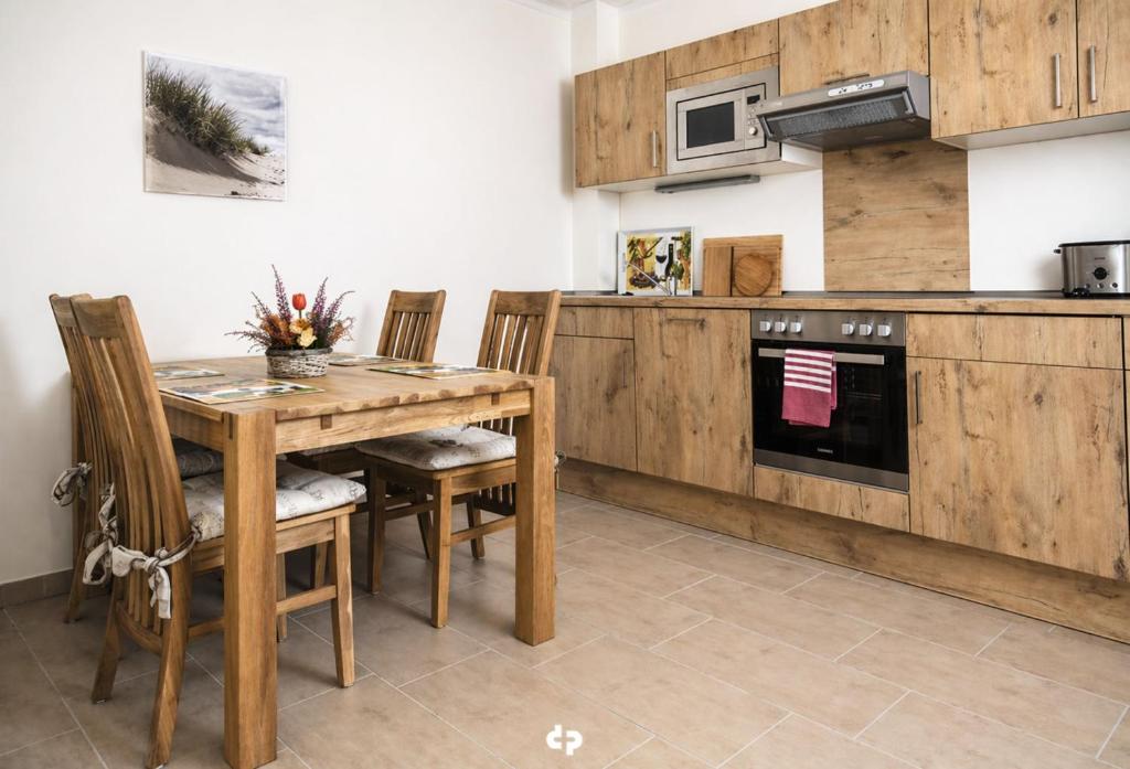 a kitchen with a wooden table and chairs and a stove at DUENENZEIT App Nr 5 max 4 Pers in Dierhagen