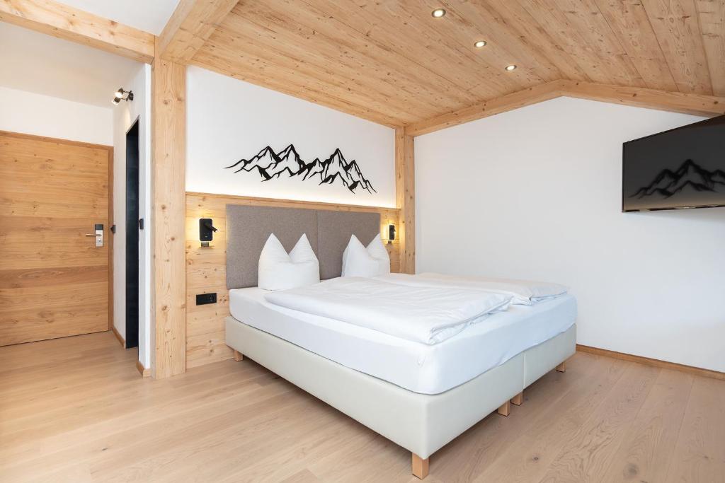 a bedroom with a white bed and a tv at Hotel Sonnenspitz *** in Kochel