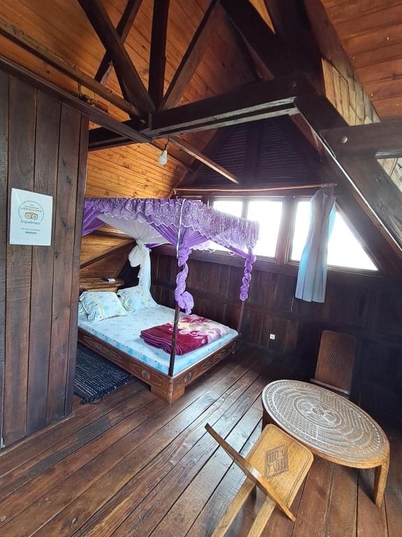 an attic room with a bed and a table in it at Hotel Anjara in Ambositra