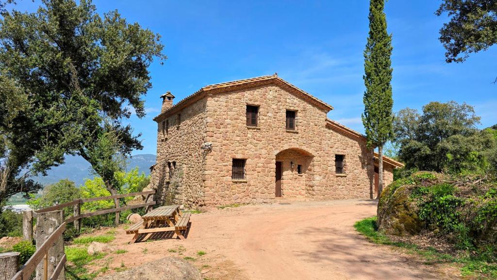 a stone building with a bench on a dirt road at Mas Morrenyà - Casa rural in Sant Jaume de Llierca