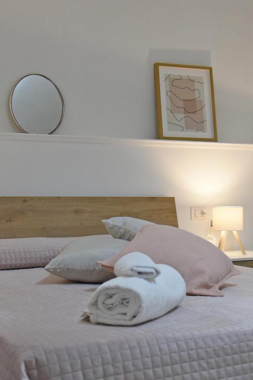 a white bed with two pillows and a mirror at DOMUS Canonico in Noto