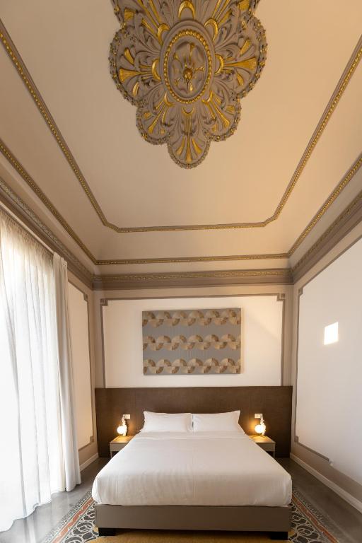 a bedroom with a large bed and a chandelier at Riflessi Acireale Palace Suites in Acireale