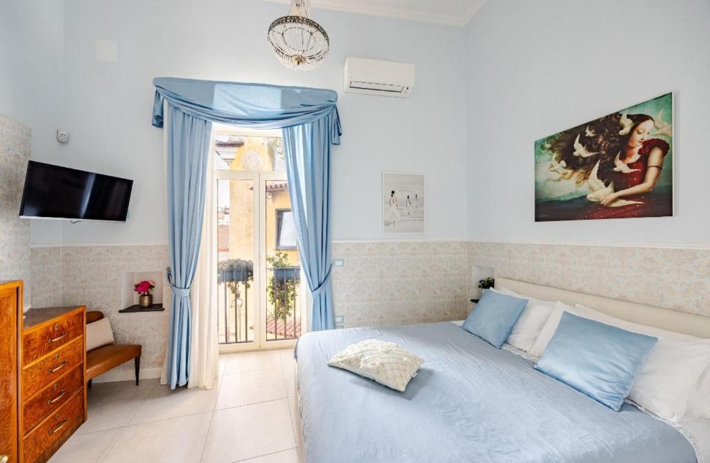 a bedroom with a bed with blue curtains and a window at Casa Parravano - Dimora storica vicino alla Reggia in Caserta