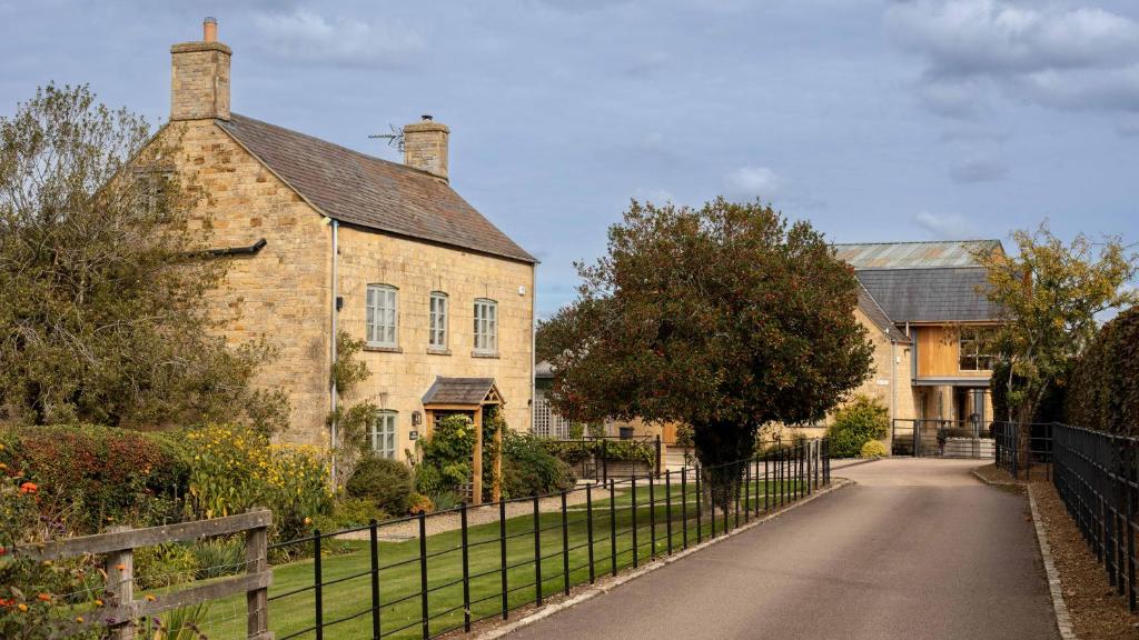 an old brick house with a fence in front of it at Lower Farmhouse in Todenham