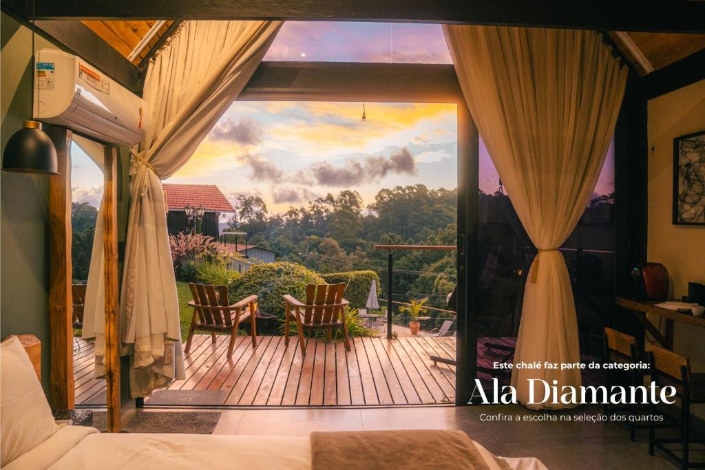 a room with a balcony with a view of a deck at Pousada das Pedras in Monte Verde