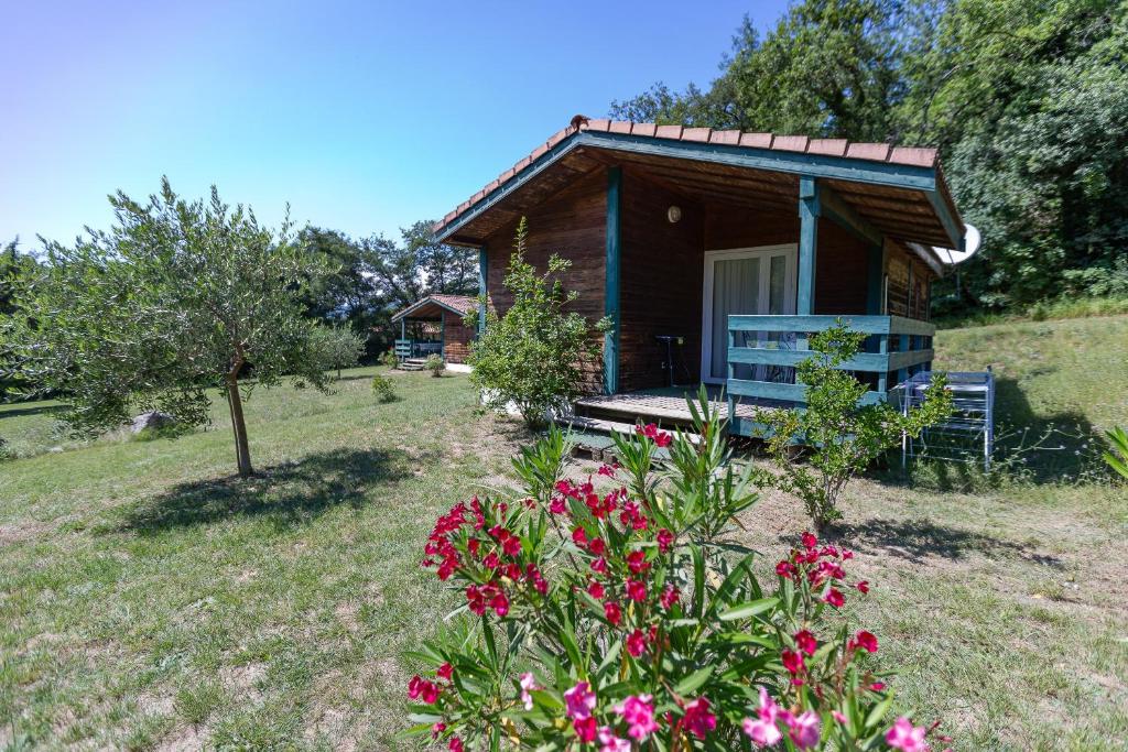 a small cabin with a bench in a field with flowers at Chalet D'alpion Nord avec Piscine in Les Tourrettes