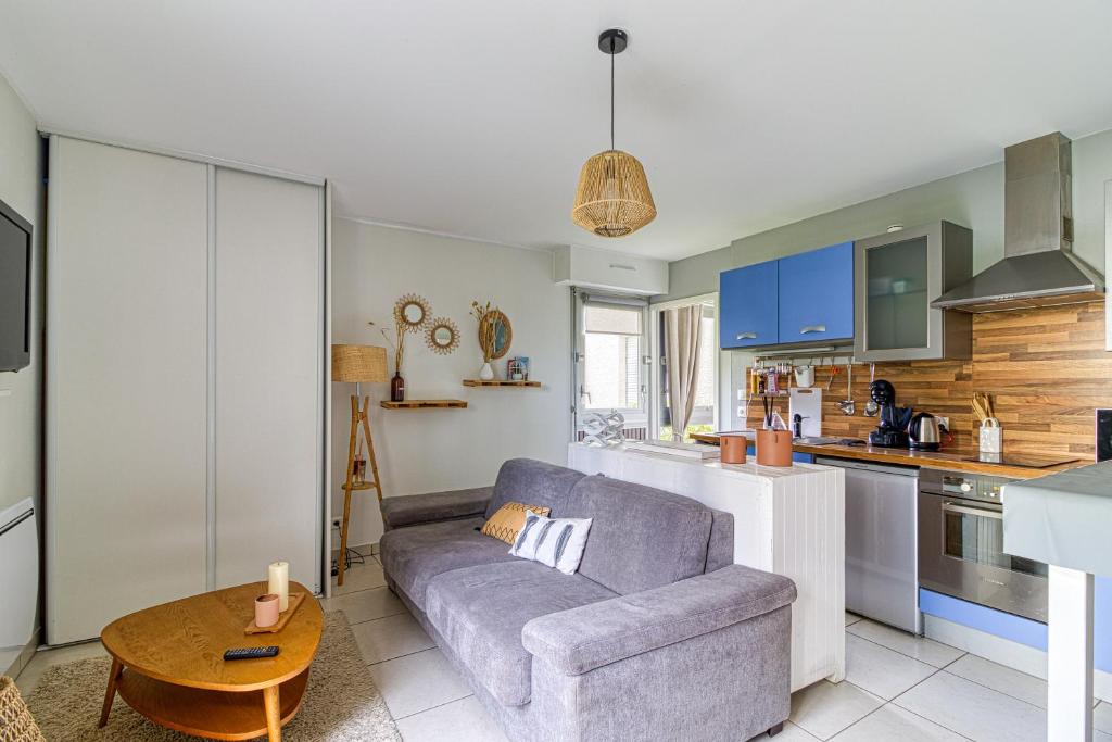 a living room with a couch and a table in a kitchen at Entre Dunes et Forêt - Proche Plage in Cucq
