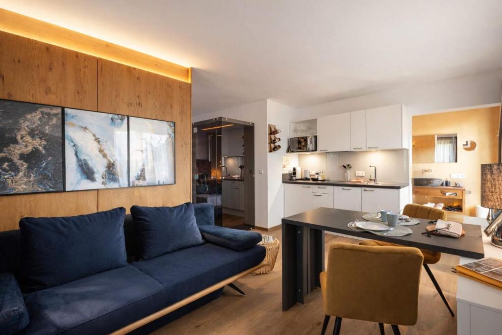 a living room with a blue couch and a kitchen at Aparthotel Viktorias Home in Kufstein