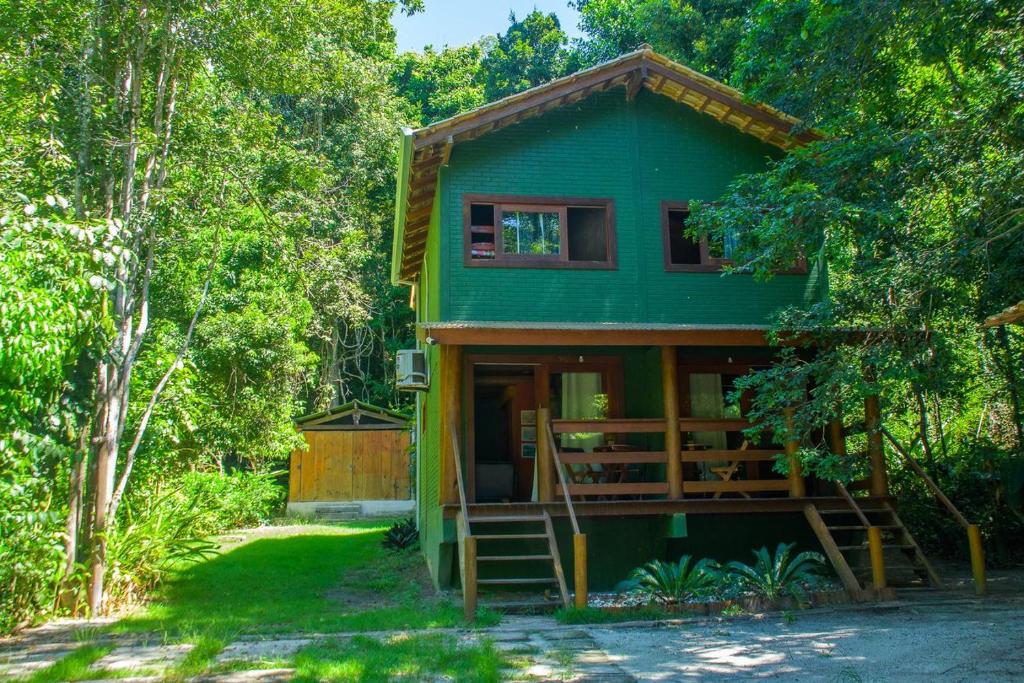a green house in the middle of trees at Chale 1 com Churrasqueira e Ar a 200m da Praia in Prado