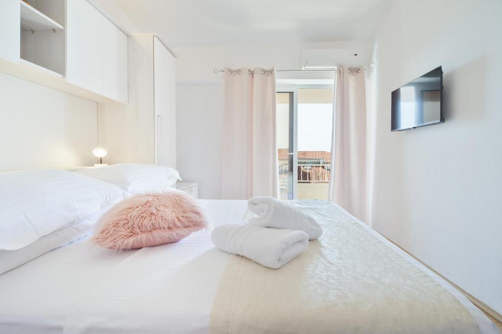 a white bedroom with two pillows on a bed at Apartment & Rooms Meri Tučepi in Tučepi