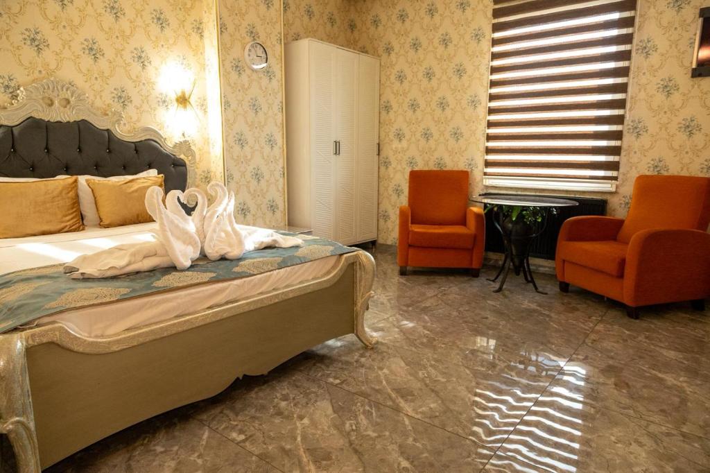a bedroom with a bed and two orange chairs at Safir Hotels Silivri in Silivri