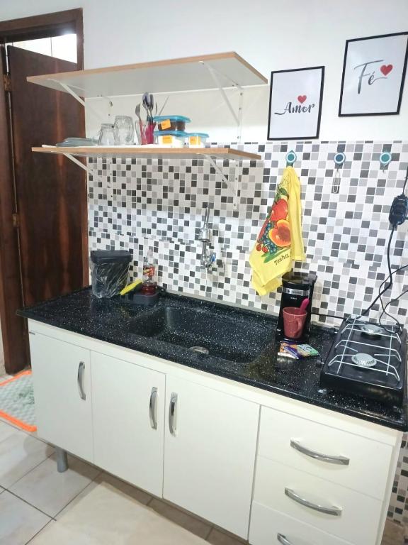 a kitchen with a sink and a black counter top at Harmonia Studio Mobiliado in Campo Grande