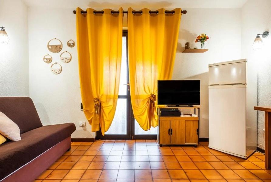 a living room with yellow curtains and a television at Il Posto Giusto in Costa Rei