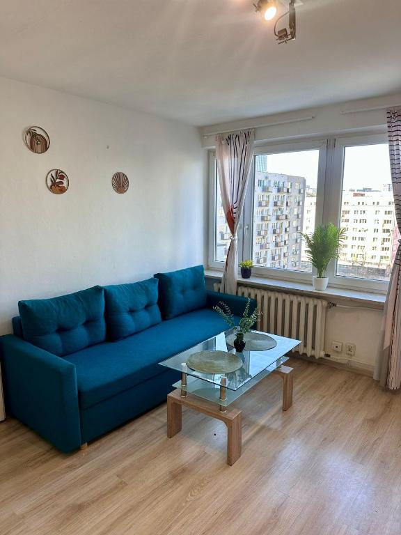 a living room with a blue couch and a table at Metro Central 3 Rooms Apartment in Warsaw