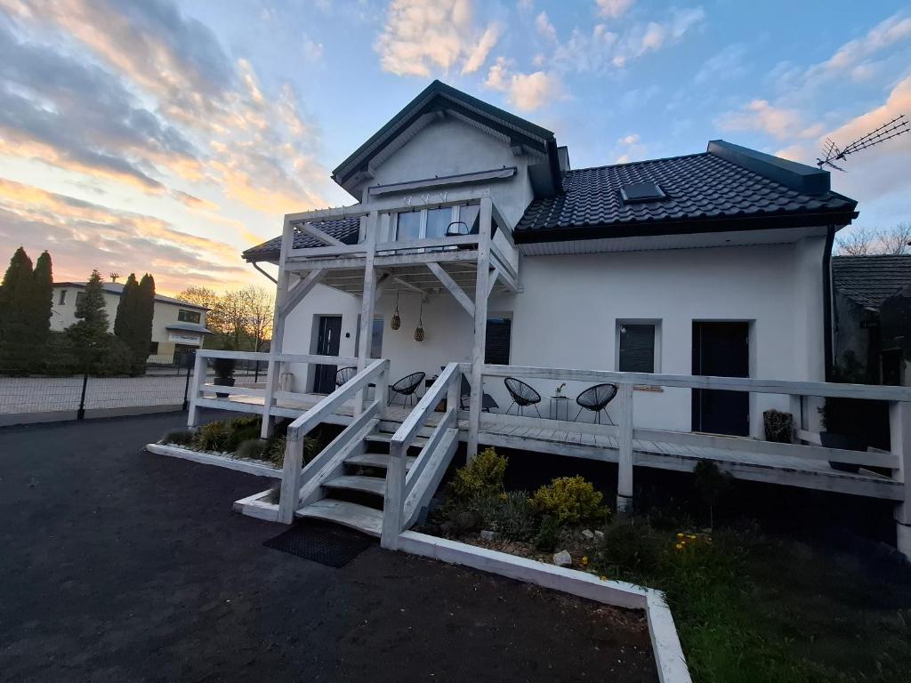 a white house with a porch and a fence at ApartamentyM&K in Balice